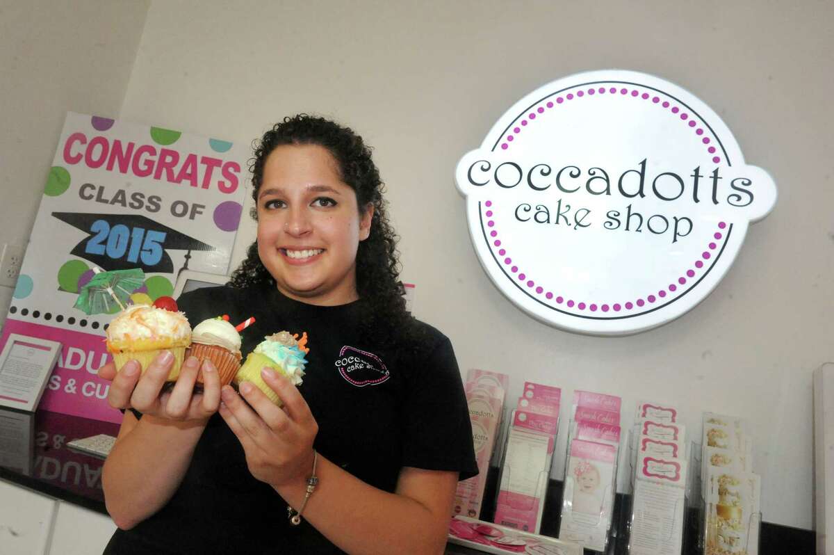 Jennifer Gavens holds three of the new summer flavors of cupcakes, pi?–a colada, root beer float and caramel & sea salt at Coccadotts bakery on Tuesday June 16, 2015 in Albany, N.Y. (Michael P. Farrell/Times Union)