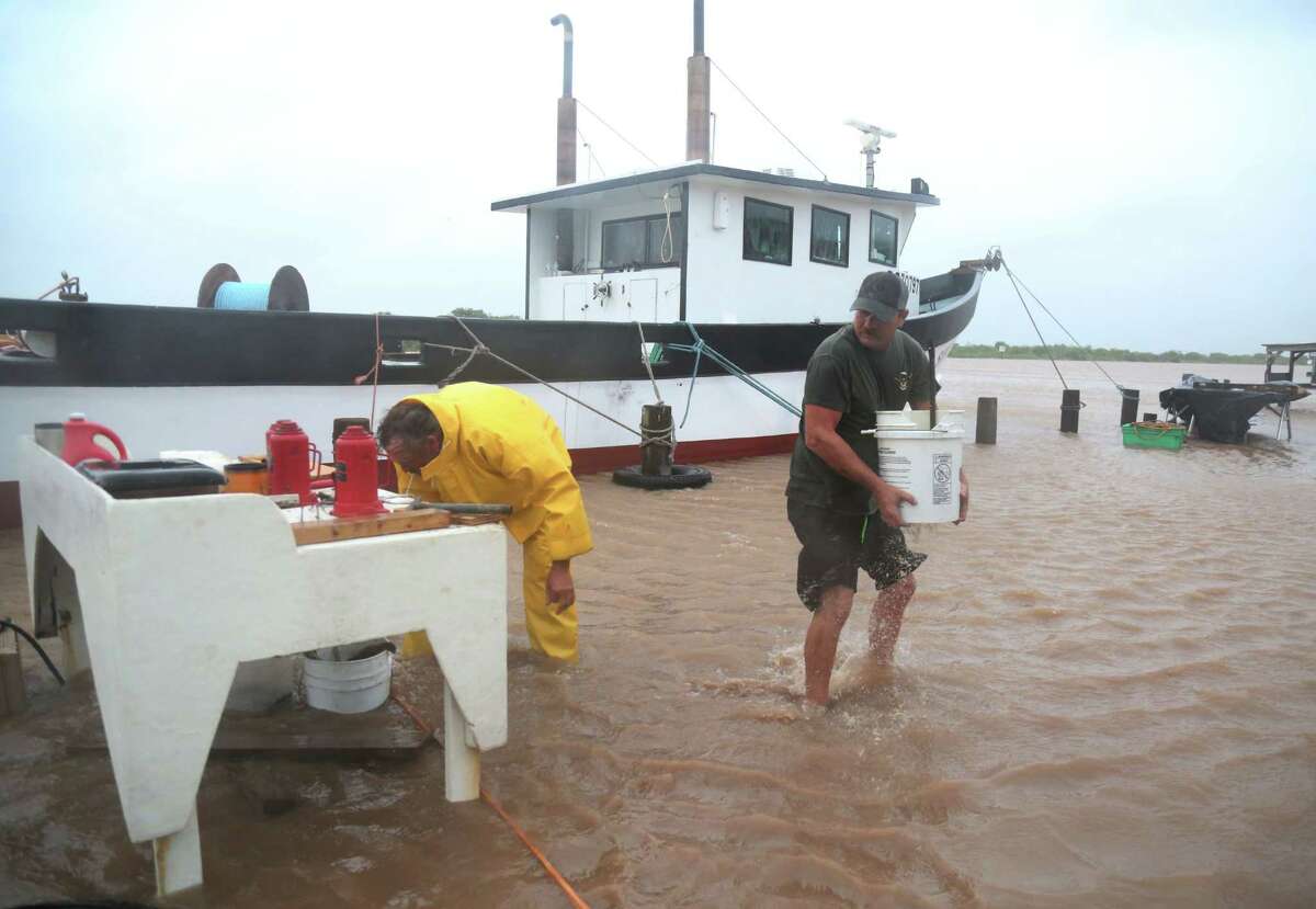 Kirk Vossler and John Bryant move items away from Colorado River floodwaters in Matagorda.