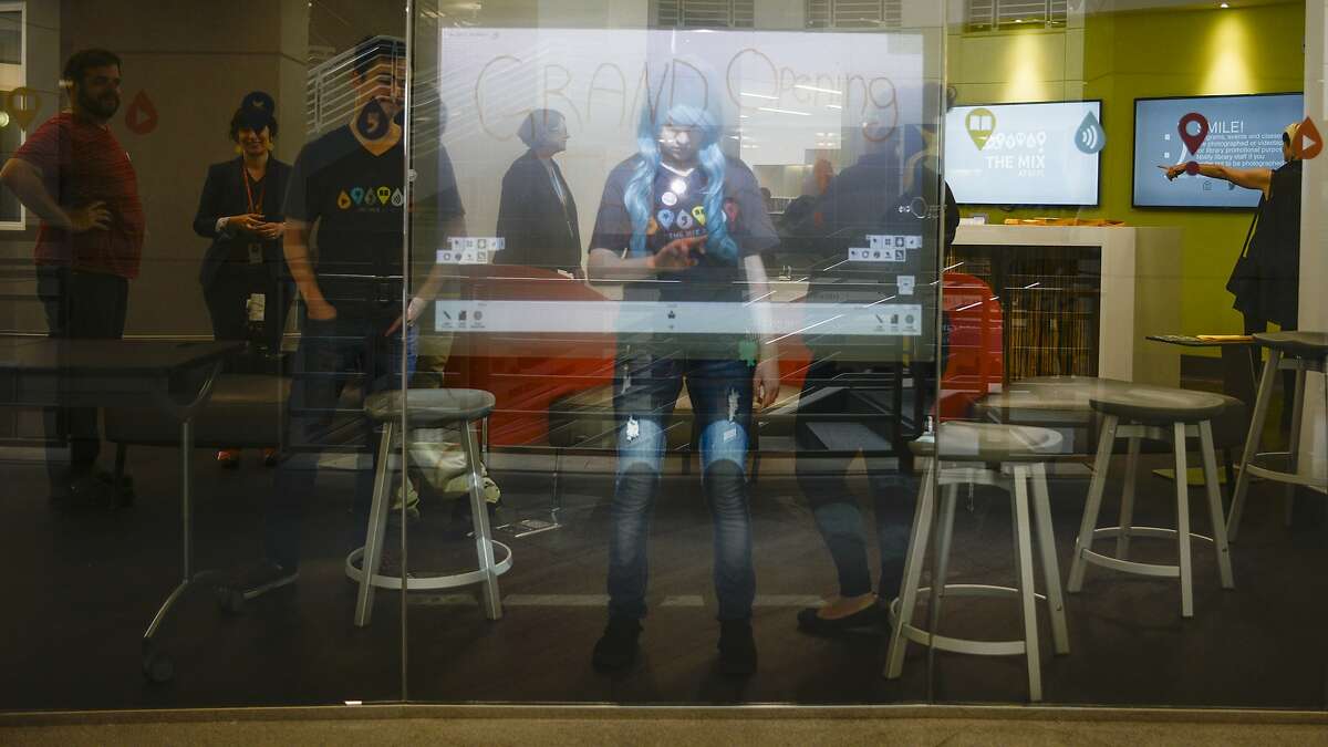 Dayra Banales draws on an interactive glass window at the opening of The Mix at San Francisco Public Library in San Francisco, California, on Thursday, June 18, 2015.