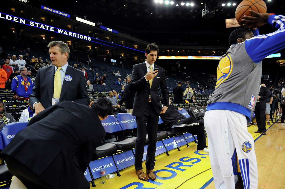 Golden State Warriors general manager Bob Myers checks his phone as players warm up before their game against the Brooklyn Nets at Oracle Arena in Oakland, CA Saturday, February 22, 2014.