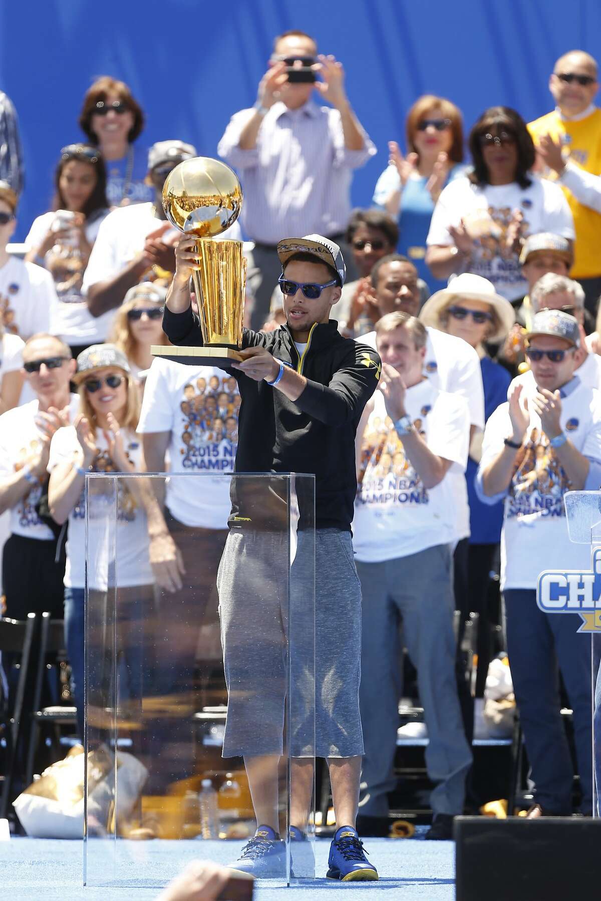 Golden State Warriors' Stephen Curry hoists the trophy after being introduced during the NBA Champions rally at the Henry J. Kaiser Convention Center on Friday, June 19, 2015 in Oakland, Calif.