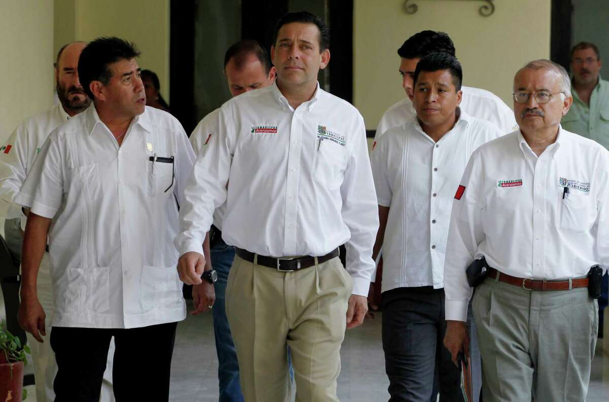 Eugenio Hernández Flores (center) is charged with conspiring to launder money and operat- ing an unlicensed money transmitting firm.