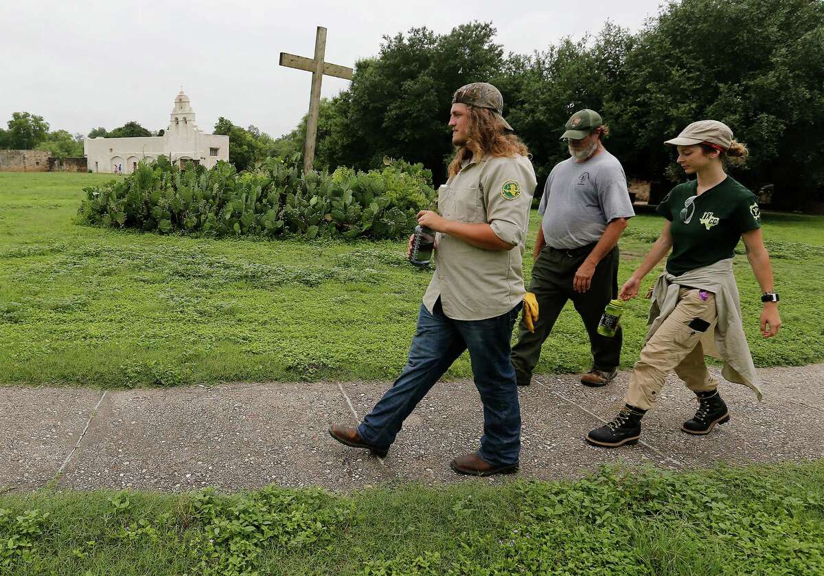 Members of the Texas Conservation Corps of Americorps Stephen McCandless (left) and Phoebe Smith (right) walk with park staffer Steve Siggins along the grounds of Mission San Juan Capistrano after a ceremony to mark the expansion of lands around the San Antonio Missions in order to preserve the land and environment on Friday, June 19, 2015. The group is helping with preservation work on the Tufa House at San Juan. "The San Antonio Missions Historical Park protects our nation's largest collection of Spanish colonial resources, and today we extend that protection even further, enhancing the experience of visitors to the Missions and vastly expanding the park's economic impact on the city of San Antonio," said Suzanne Dixon of the National Parks Conservation Association in a press release. The San Antonio River Authority and the City of San Antonio will transfer about 60.5 acres of land around Mission San Juan to the National Park Service as part of the preservation efforts. (Kin Man Hui/San Antonio Express-News)