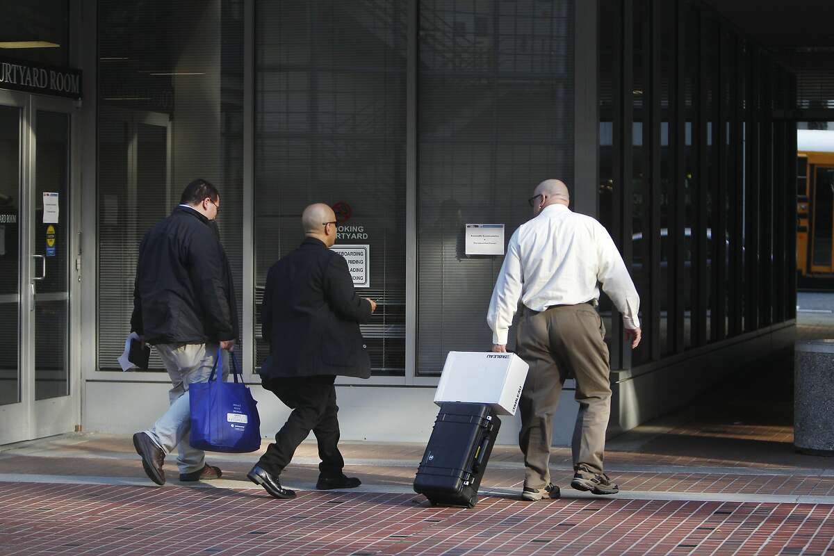 CAPTION BEING CONFIRMED. DO NOT USE UNTIL THIS NOTE REMOVED. Representatives with the California Attorney General's office carry a bag and rolling case with a box as they leave the California Public Utilities Commission offices on Thursday, November 6, 2014 in San Francisco, Calif.
