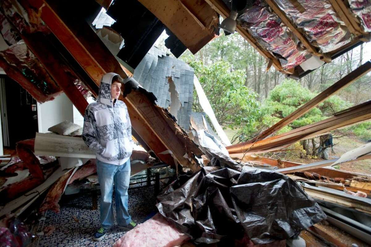 Aaron Maiolo, 16, poses in the living room where he was on the couch when a tree tore through the roof during Saturday's storm at his family's home on Red Fox Road in Stamford, Conn. on Monday, March 15, 2010.