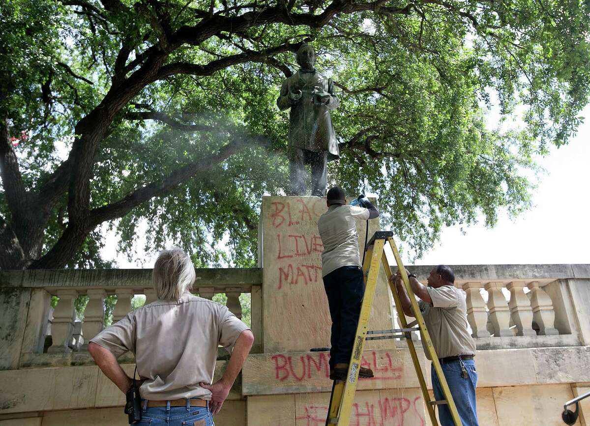 Sergio Martinez, center, with UT Facilities Services, pressure washes a statue of Jefferson Davis to remove graffiti at the University of Texas campus in Austin, Texas, on Tuesday, June 23, 2015. Cindy Posey, spokeswoman for campus security at UT, says “Black lives matter” was scrawled early Tuesday on the base of the statue to the president of the Confederacy, and also on those for Confederate Gens. Robert E. Lee and Albert Johnston. (Dborah Cannon/Austin American-Statesman via AP) AUSTIN CHRONICLE OUT, COMMUNITY IMPACT OUT, INTERNET AND TV MUST CREDIT PHOTOGRAPHER AND STATESMAN.COM, MAGS OUT