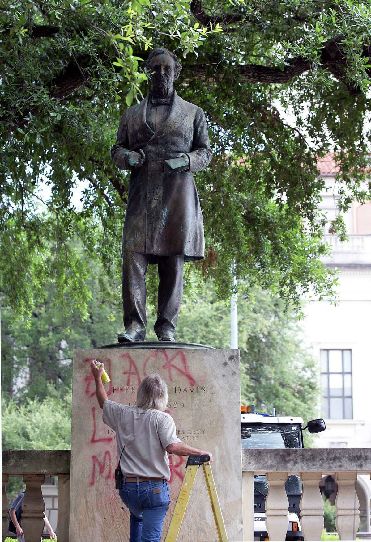 Bill Tanner with UT Facilities Services works to remove graffiti from a statue of Jefferson Davis on the south mall at the University of Texas campus in Austin, Texas, on Tuesday, June 23, 2015. Cindy Posey, spokeswoman for campus security at UT, says “Black lives matter” was scrawled early Tuesday on the base of the statue to the president of the Confederacy, and also on those for Confederate Gens. Robert E. Lee and Albert Johnston. (Dborah Cannon/Austin American-Statesman via AP) AUSTIN CHRONICLE OUT, COMMUNITY IMPACT OUT, INTERNET AND TV MUST CREDIT PHOTOGRAPHER AND STATESMAN.COM, MAGS OUT