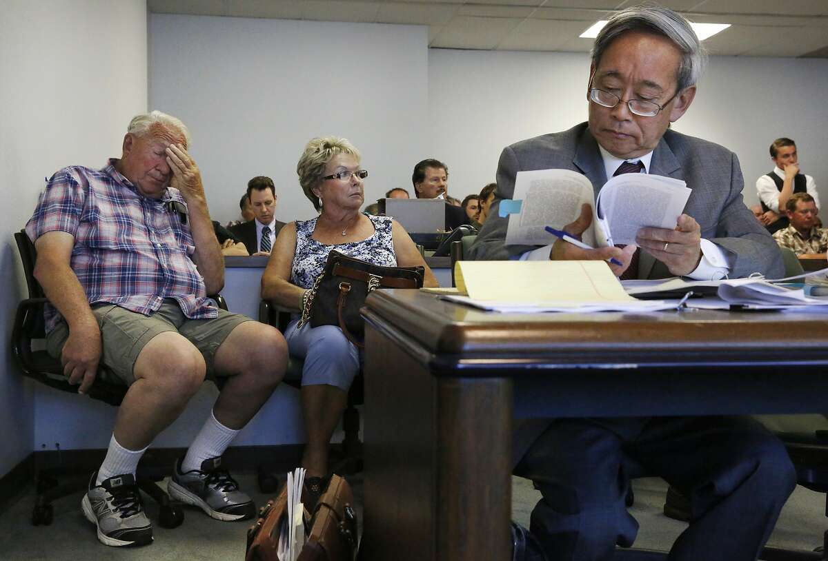 Farmer Bernie Dietz, 75, sits with his wife Greta, left, while the attorney for the State Water Board Clifford Lee, right, reads over literature during a hearing between the State Water Board and the Banta-Carbona Irrigation District June 23, 2015 in Stockton, Calif. The hearing was expected to determine whether the state water board can legally stop diversions in the water district.