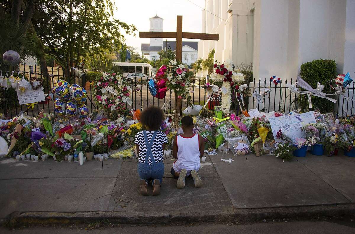 TOPSHOTS Two children pray near thousands of flowers and cards left in condolence outside Emanuel AME Church in Charleston, South Carolina, on June 23, 2015. Police captured the white suspect in a gun massacre at one of the oldest black churches in the United States, the latest deadly assault to feed simmering racial tensions. Police detained 21-year-old Dylann Roof, shown wearing the flags of defunct white supremacist regimes in pictures taken from social media, after nine churchgoers were shot dead during bible study on June 17. AFP PHOTO/JIM WATSONJIM WATSON/AFP/Getty Images