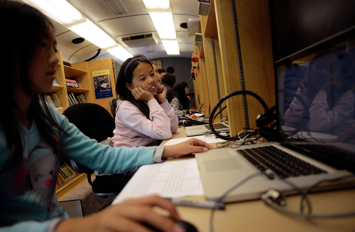 Connie Ma, 10 (center), watches Ashley Liang, 10 (left), look for photos for her storyboard inside the Tech Mobile bus, among the S.F. library’s new tech tools, in front of the Visitacion Valley Boys and Girls Club. .