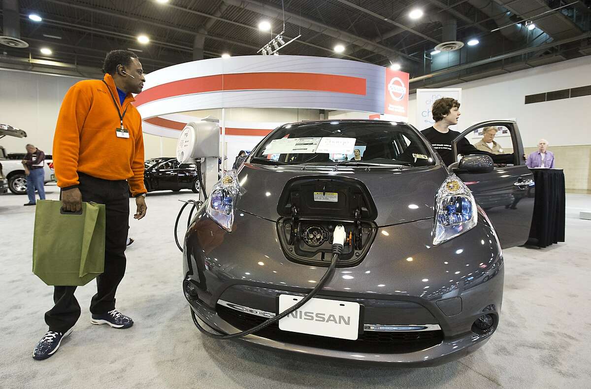FILE - In this Jan. 22, 2014 file photo, Keith Mack, from Stafford, Texas, looks at the Nissan Leaf at the Houston Auto show at Reliant Center in Houston. U.S. sales of electric cars were up 35 percent last year, to 65,347, according to Ward's AutoInfoBank. (AP Photo/Houston Chronicle, Thomas B. Shea, File)