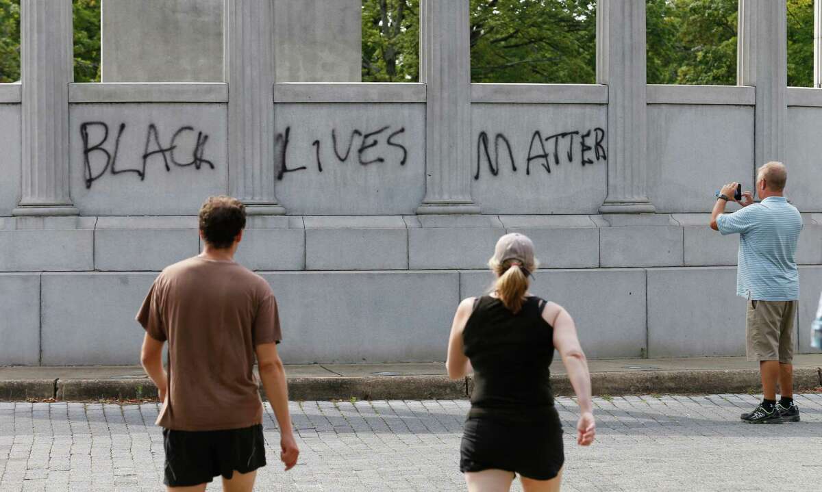 A passerby photographs the spray painted message of âBlack Lives Matterâ that was painted on a monument to former Confederate President Jefferson Davis on Monument Avenue in Richmond, Va., Thursday, June 25, 2015. The vandalism comes after a mass shooting in Charleston South Carolina has sparked a nationwide debate on the public display of Confederate imagery. (AP Photo/Steve Helber)