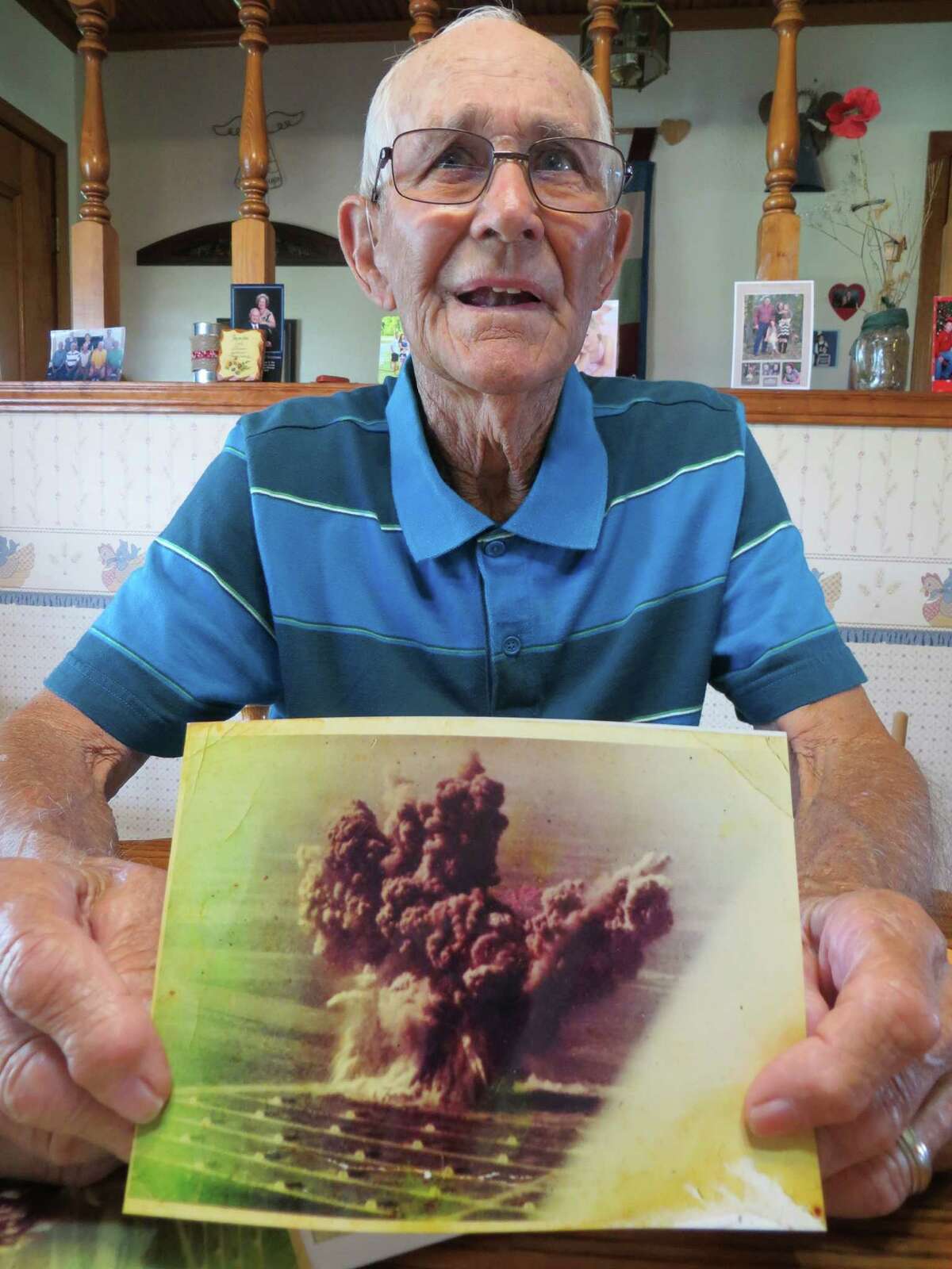 Louis Ehlinger Sr. of Devine recalls how he survived the Nov. 13, 1963, blast of high explosives stored at Medina Base Annex that broke windows in downtown San Antonio and created a mushroom cloud, which can be seen in a photo he displayed.