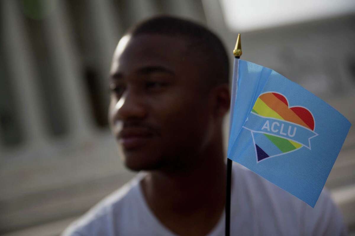 Demonstrator Michael Abney holds a miniature rainbow American Civil Liberties Union (ACLU) flag outside the U.S. Supreme Court in Washington, D.C., U.S., on Friday, June 26, 2015.