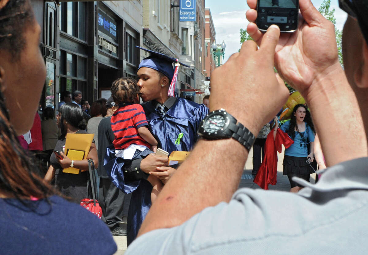 Isaiah Belle lll of Schenectady kisses his 1-yr-old son Isaiah Belle lV while his father Isaiah Belle ll takes a photo of them after the graduation ceremony for Schenectady High School at Proctors on Friday, June 26, 2015 in Schenectady, N.Y. The graduate's sister Iaisa Belle stands at left. (Lori Van Buren / Times Union)