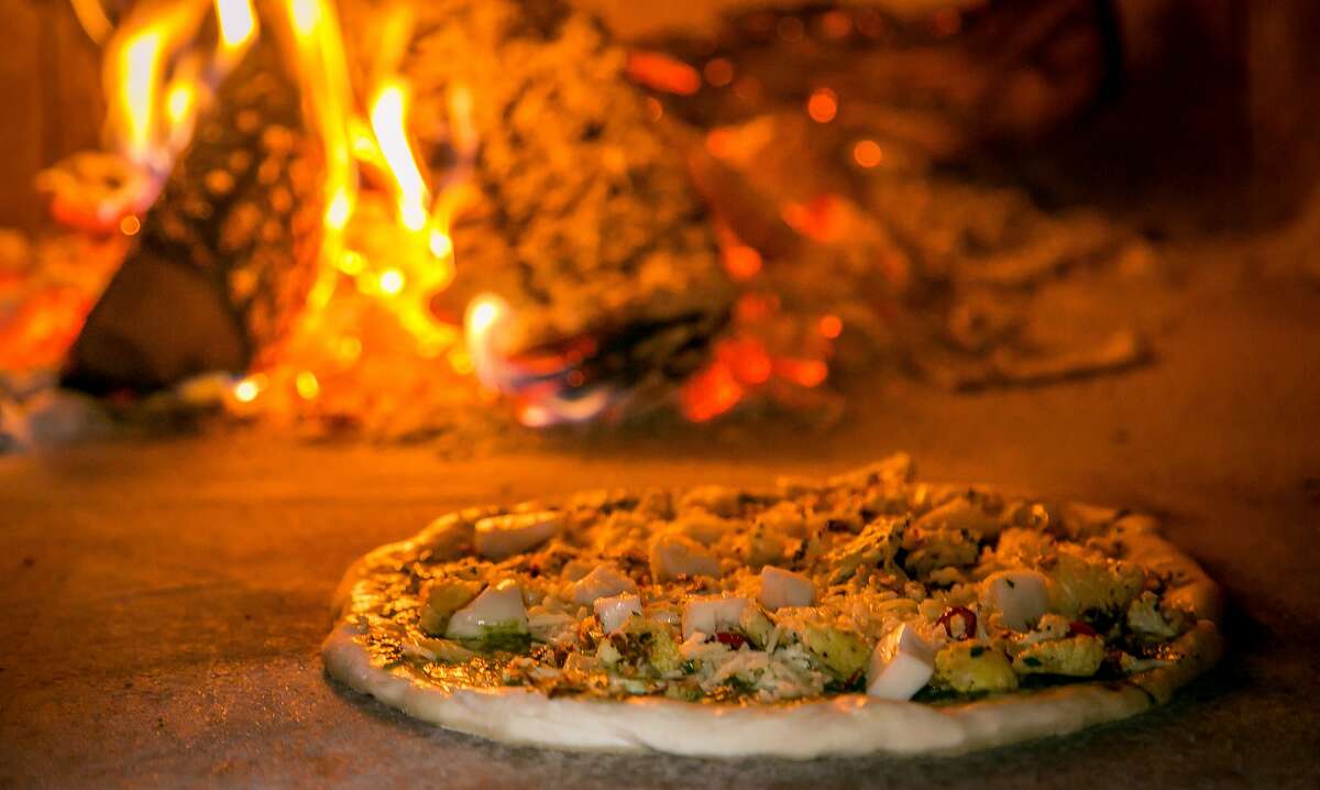 The Cauliflower with Nettle pesto pizza cooks in the wood burning oven at Parlour in Oakland, Calif., on June 26th, 2015.