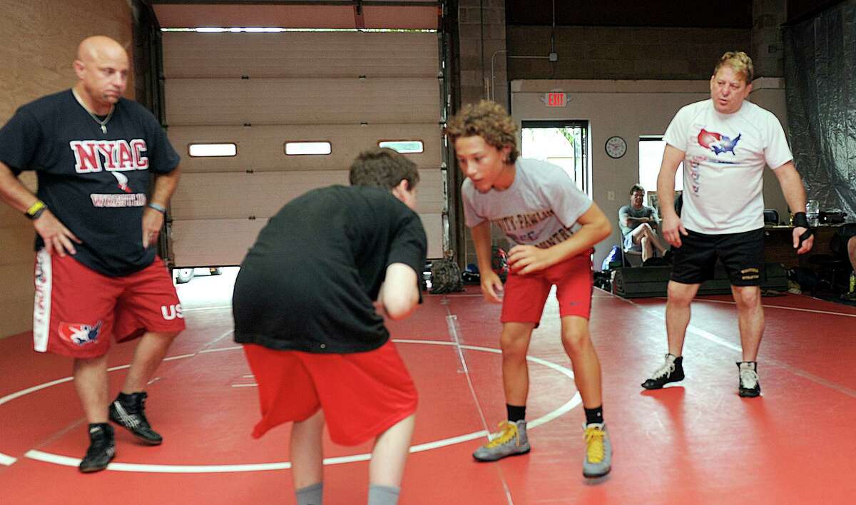 John Kijek, left, a USA wrestling coach and Former University of Iowa wrestling coach and two-time NCAA champion Royce Alger instruck Max Lynch, 14, of Bethel, and David Brancroft, 14, of Brewster during a camp at the Connecticut Wrestling Academy.