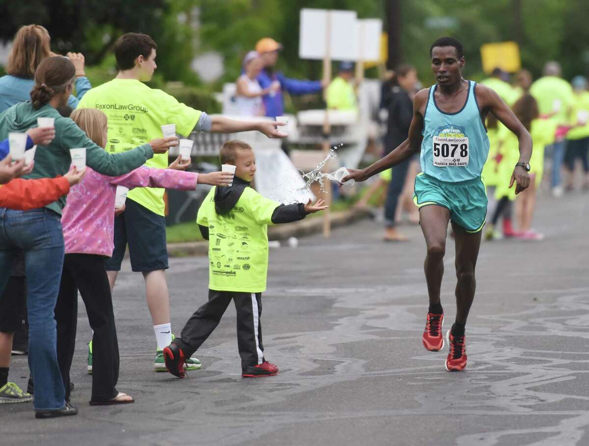 Gosa Girma Tefera, of Ethiopia, grabs a cup of water coming down the final stretch of the Faxon Law Group Fairfield Half Marathon at Jennings Beach in Fairfield, Conn. Sunday, June 28, 2015. Gosa Girma Tefera, of Ethiopia, was the first place overall finisher with a time of 1:04:05 and Etaferahu Temesgen, of Ethiopia, was the first female finisher with a time of 1:14:09.