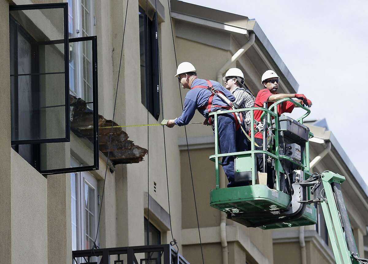 FILE- In this Wednesday, June 17, 2015 file photo, a worker measures near the remaining wood from an apartment building balcony that collapsed in Berkeley, Calif. The balcony broke loose from the building during a 21st birthday party early Tuesday, June 16, 2015, killing several people and seriously injuring others. Prosecutors in the San Francisco Bay Area say they will lead a criminal investigation into the Berkeley balcony collapse that killed six college students. The development comes after building inspectors said the fifth-floor balcony that snapped off an apartment building was supported by wooden beams badly rotted by exposure to moisture.