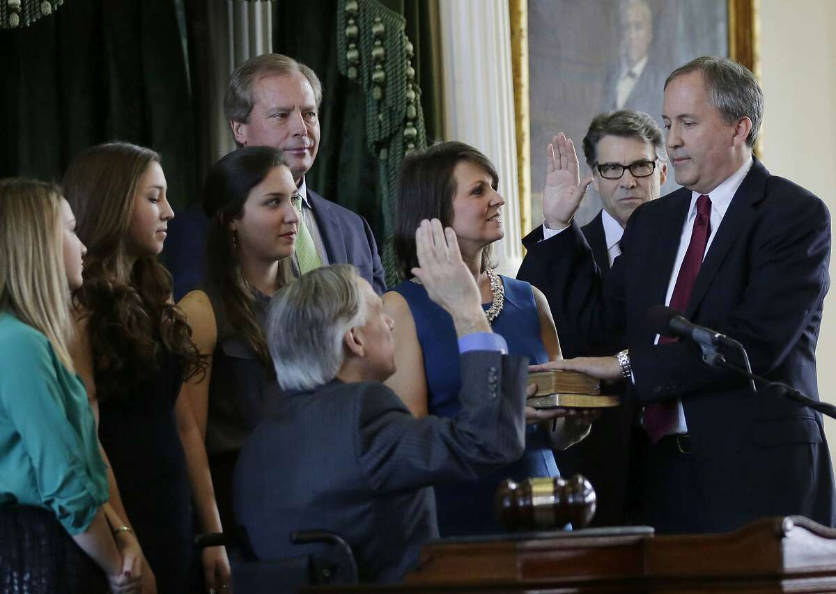 Ken Paxton, right, is sworn in as Texas attorney general by Gov.-elect Greg Abbott, center, Monday, Jan. 5, 2015, in Austin, Texas. Paxton is joined by his family and Gov. Rick Perry, second from right. (AP Photo/Eric Gay)