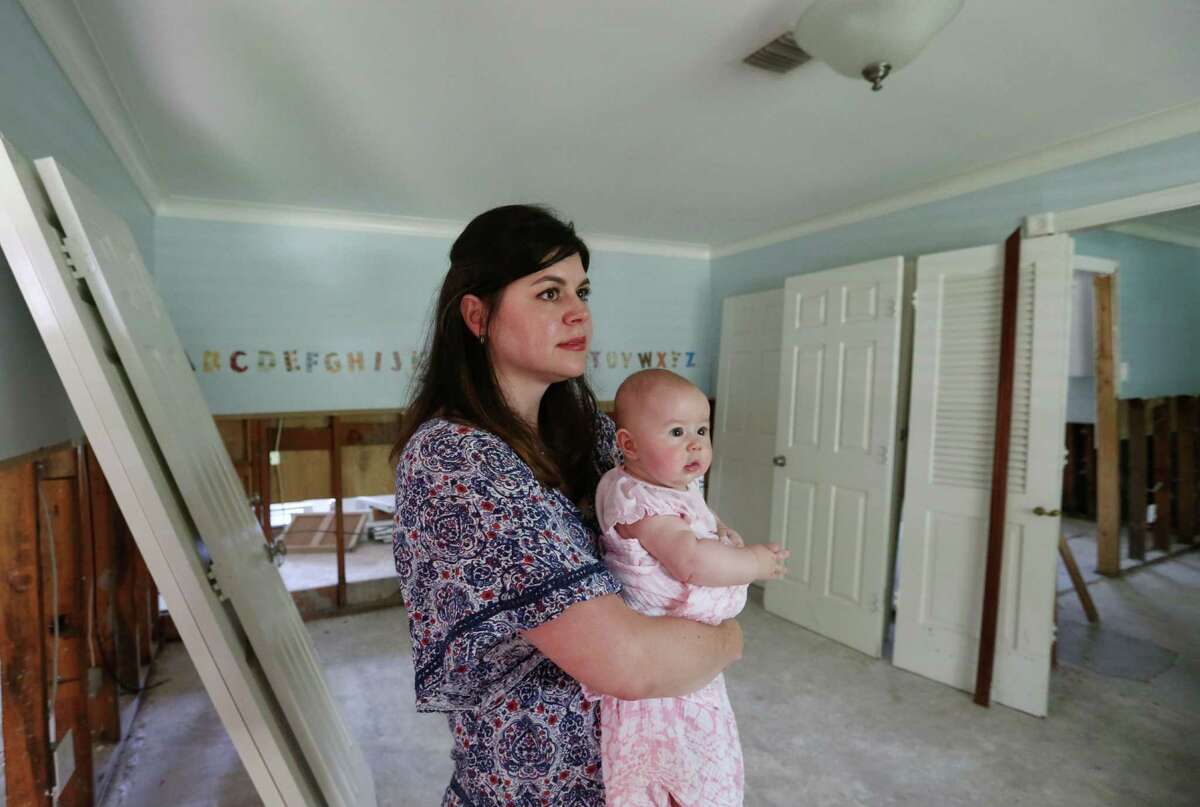 Emily Ervin and her four month old daughter Tessa stand in the play room of their family's flood-damaged Meyerland home Friday, June 26, 2015, in Houston. "We want to rebuild, we just can't afford to do it," she said. "We want nothing more than to stay."