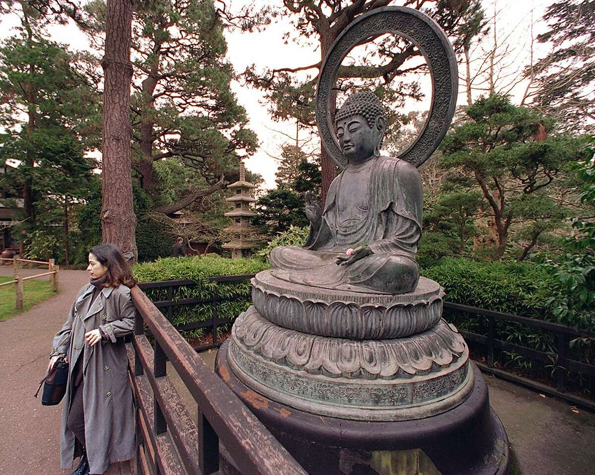 纪念物2/C/20DEC96/CD/CS -一名游客在金门公园日本茶园的铜像前留念。这座纪念碑于206年前在日本铸造，目前需要近8.1万美元的维修费用。旧金山纪事摄影克里斯·斯图尔特
