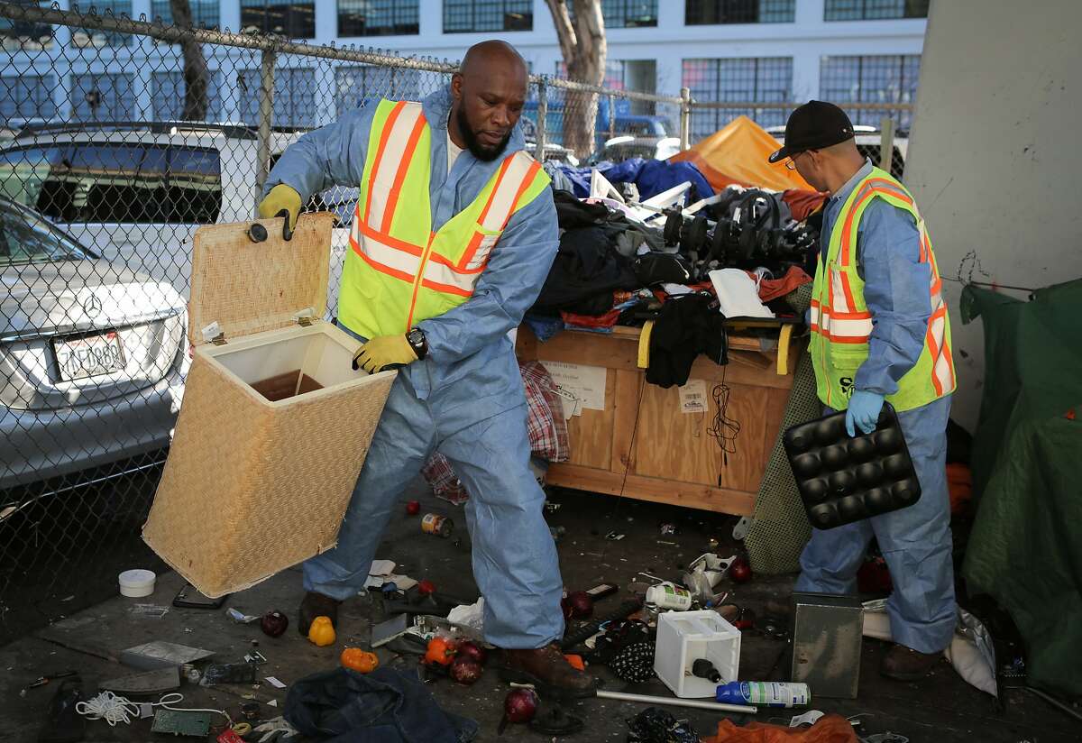 Bernard Sices (left) and Yu Chun Jin, employees of the San Francisco Public Works Department's "alley crew", round up debris to be hauled away from a homeless encampment at 8th and Brannan Streets in San Francisco, California, on Wednesday, July 1, 2015. The alley crew visits homeless encampments on a daily basis to disinfect the ground and haul away refuse.