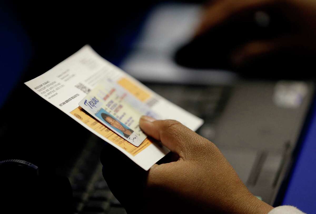 In 2014, an election official checks a voter's photo identification at an early voting polling site in Austin, Texas. The 5th Circuit Court of Appeals on Wednesday ruled against the state’s voter ID law, saying it had discriminatory effect.