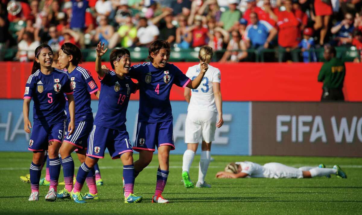 Saori Ariyoshi and Saki Kumagai celebrate as England's Laura Bassett buries her face into the pitch after an errant tip gave Japan the winning goal in stoppage time.