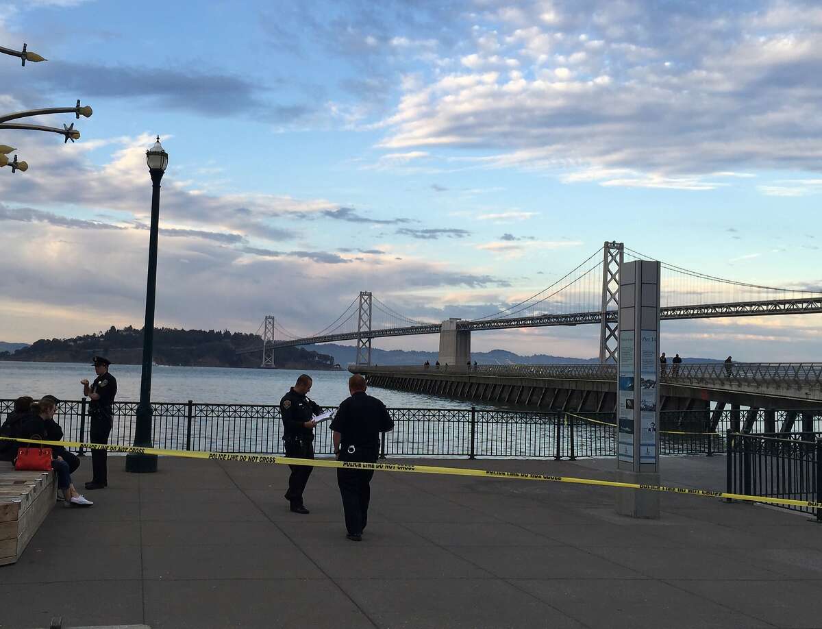 Police investigators at Pier 14 on San Francisco's Embarcadero about 90 minutes after a woman was shot on the long narrow pedestrian pier. The people sitting on the left are passers-by who were on the scene when the fatal shooting occurred.