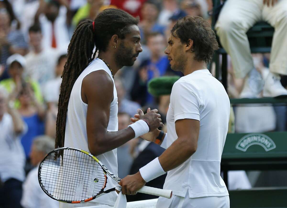 Dustin Brown of Germany, left, shakes hands at the net with Rafael Nadal of...