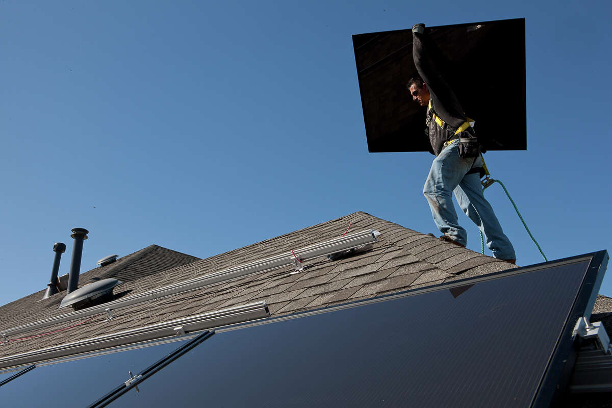 A worker with a solar installation company prepares to install a rooftop system. CPS Energy will achieve its goal of 20 percent generation from renewable sources in 2016, four years ahead of schedule.