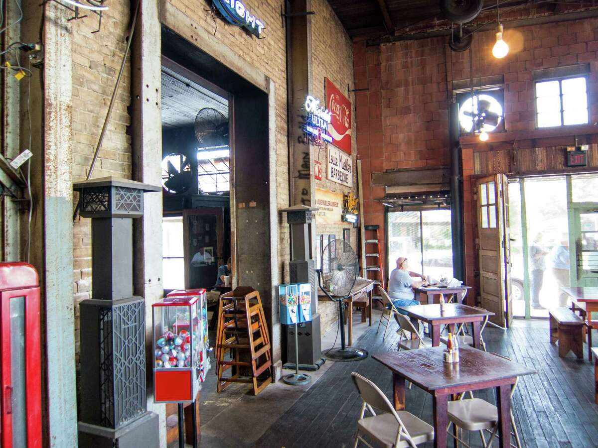 The dining room at Louie Mueller Barbecue in Taylor, above. Wayne Mueller cooks barbecue for students in Okinawa, Japan, left.