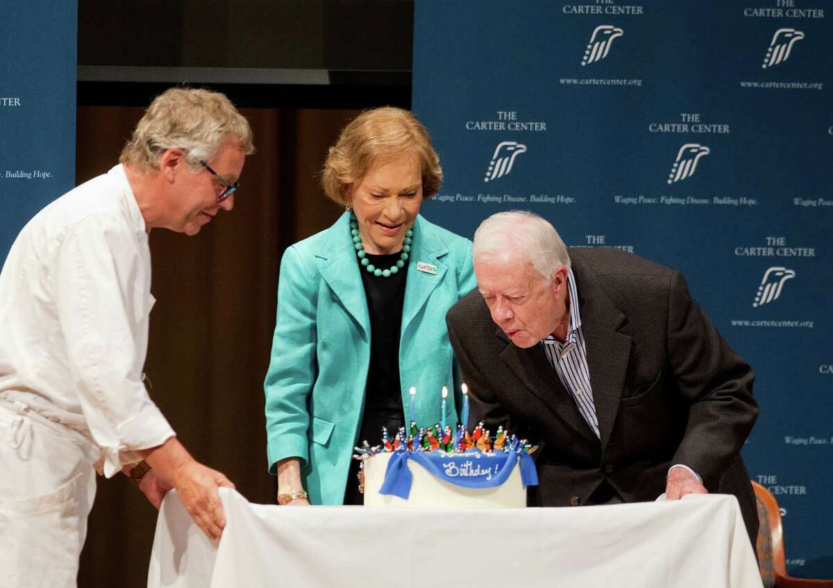 Former President Jimmy Carter, right, blows out candles on a birthday cake as wife Rosalynn looks on during his 90th birthday celebration in Atlanta.