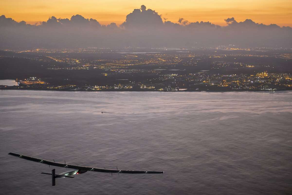 In this photo provided by Jean Revillard, Solar Impulse 2, a plane powered by the sun's rays and piloted by Andre Borschberg, approaches Kalaeloa Airport near Honolulu, Friday, July 3, 2015. His voyage from Nagoya, Japan broke the record for the world's longest nonstop solo flight, his team said. (Jean Revillard/Global Newsroom via AP)