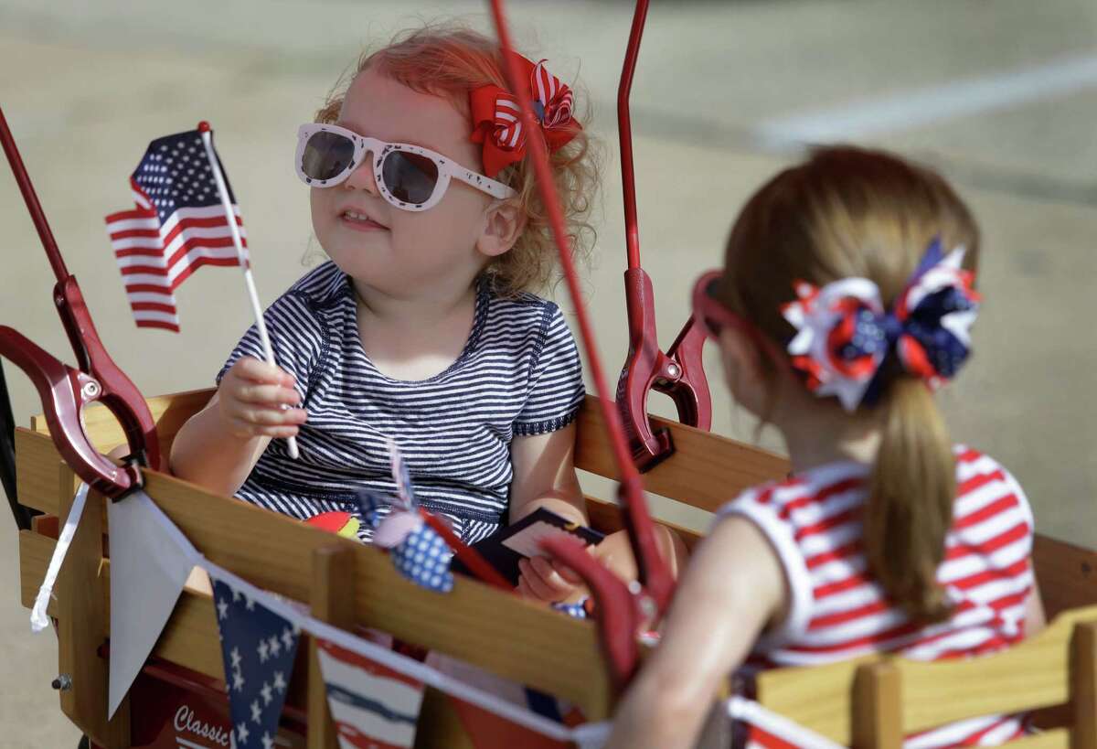 Catherine Lehpamer, 2, left, of Houston and Malley Lutschg, 2, of Bellaire ride in a wagon during the Bellaire July 4th Parade on Saturday﻿.