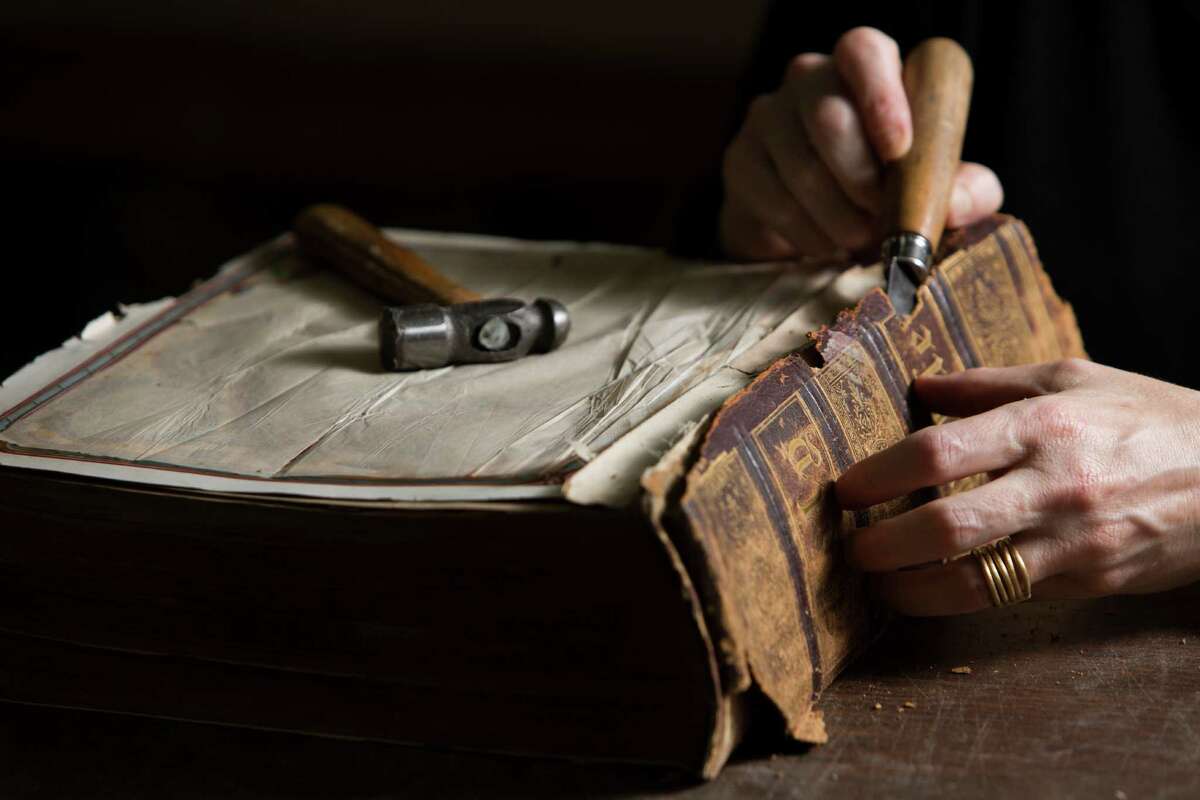 Deborah Karchmer owner of Bella Becho Book & Print Bindery removes the original spine of a 1800s Bible for restoration purposes. Thursday, June 18, 2015, in Houston.