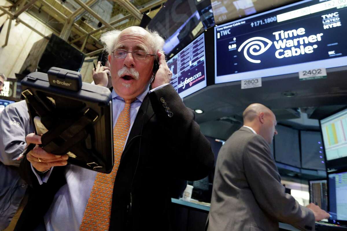 Trader Peter Tuchman (left) works the post that handles Time Warner Cable on the floor of the New York Stock Exchange, after Charter Communications announced it is buying Time Warner Cable for $55.33 billion. Companies around the world announced mergers and acquisitions worth $2.3 trillion, according to figures from data provider Dealogic.