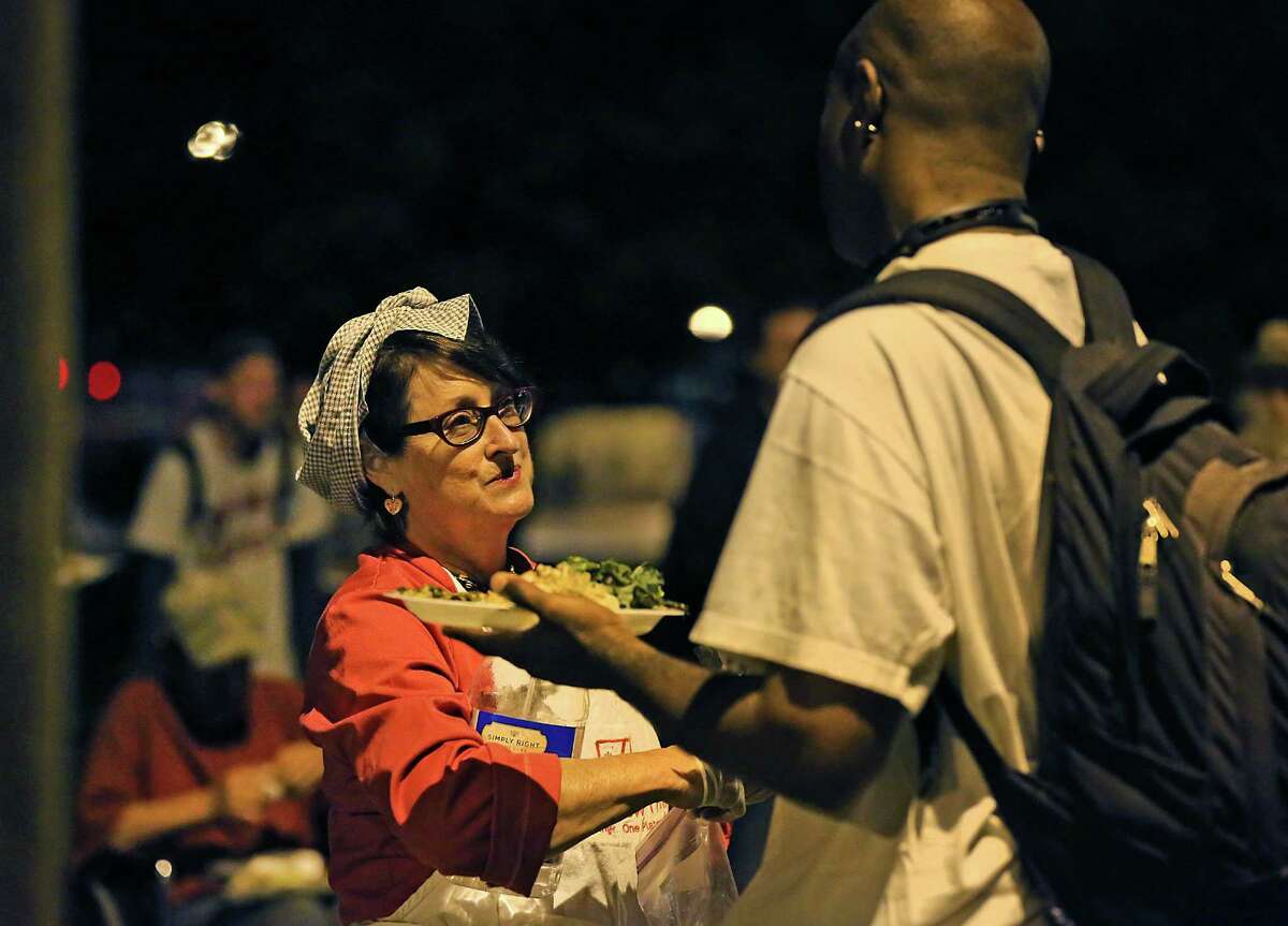 Joan Cheever, left, talks with Shaundale Whitmore after he received his plate from Cheever's food truck at Maverick Park where she fed close to 40 people who live on the streets. Tuesday, April 21, 2015.