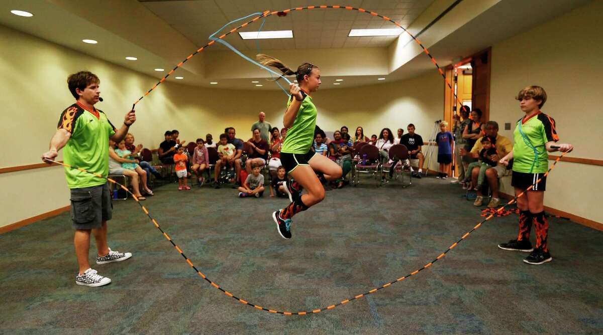 Jumper Olivia Key (center), 13, of The Jumping Dragons jump rope team demonstrates her jumping skills with coach Bobby Barrera (left) and Brinley Barrera (right) in front of an audience at Cody Library on Tuesday, July 7, 2015. Coach Barrera has been teaching jump roping for the past 16 years and the group performs at various events including Spurs games and at the Institute of Texan Culture's Folklife Festival. (Kin Man Hui/San Antonio Express-News)