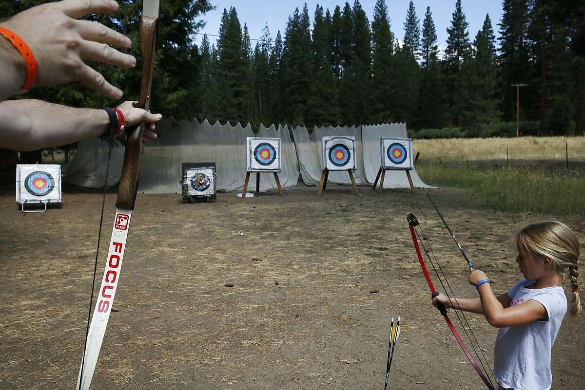 Claire Rogers Lewis, 7, prepares an arrow as her father Kevin Lewis lets one loose during a morning archery session July 8, 2015 at Mather Family Camp in Groveland, Calif. The California State Water Board's curtailment notice served to San Francisco Public Utilities Commission could affect the water supply at the popular San Francisco family summer camp.