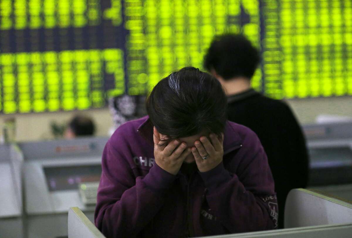 A woman rubs her face as she stands at a computer terminal in a stock brokerage house in Nantong in eastern China's Jiangsu province Wednesday, July 8, 2015. China's Shanghai Composite Index fell 5.9 percent on Wednesday. (Chinatopix via AP) CHINA OUT