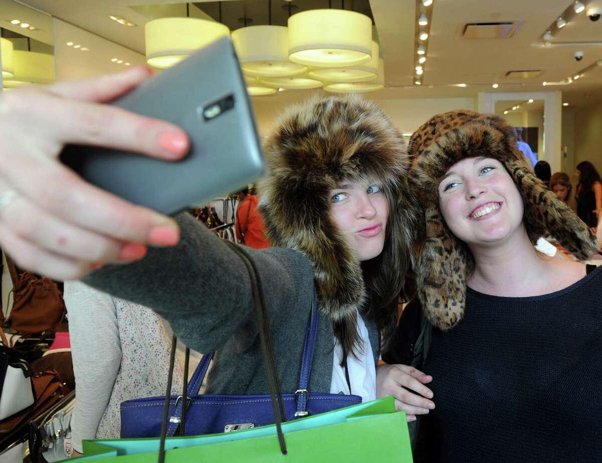 Agnieszka Krzyzanska, left, and friend, Jeanne Blin, both of Greenwich, take a selfie wearing fur hats that were part of the Michael Kors merchandise on sale during the Greenwich Chamber of Commerce sponsored event, Sidewalk Sale Days, on Greenwich Avenue and the surrounding business district, Thursday, July 9, 2015. The event is known for great retail discounts as merchants set-up kiosks in front of the businesses.