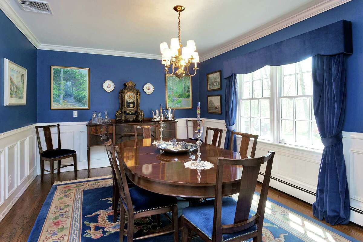 The formal living room has royal blue upper walls and wainscoting with picture-frame paneling on the lower portions.