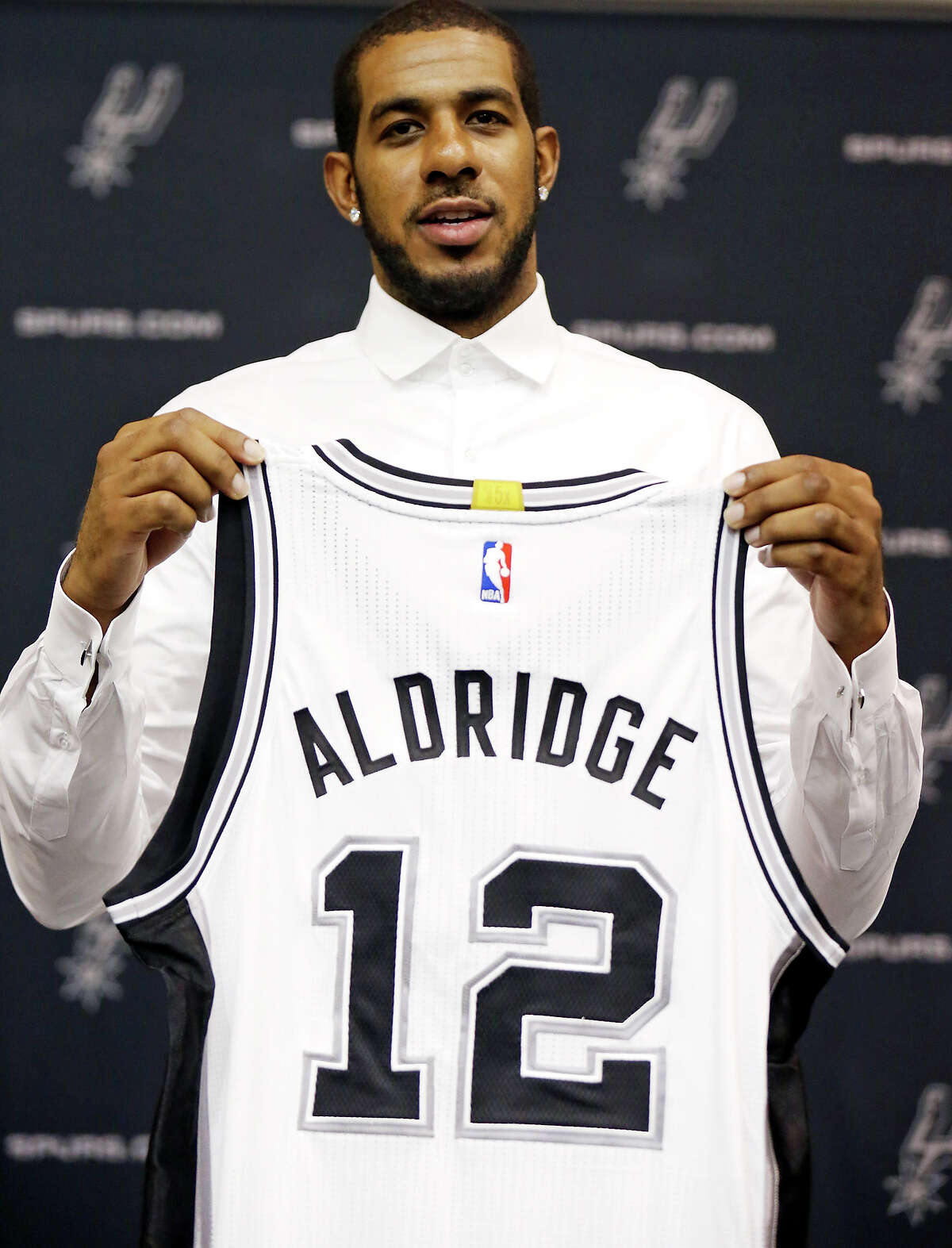 San Antonio Spurs' LaMarcus Aldridge poses for photos with his jersey during a press conference at the Spurs practice facility Friday July 10, 2015 where he was officially introduced.