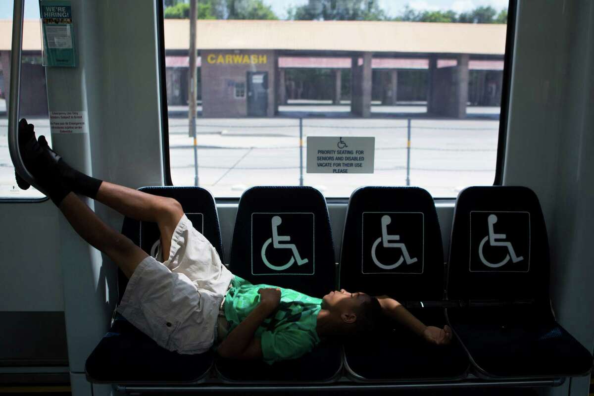 Dashawn Gagnon, 11, gets to be able to stretch taking several sits because the Metro Rail green line is empty, Friday, July 10, 2015, in Houston.