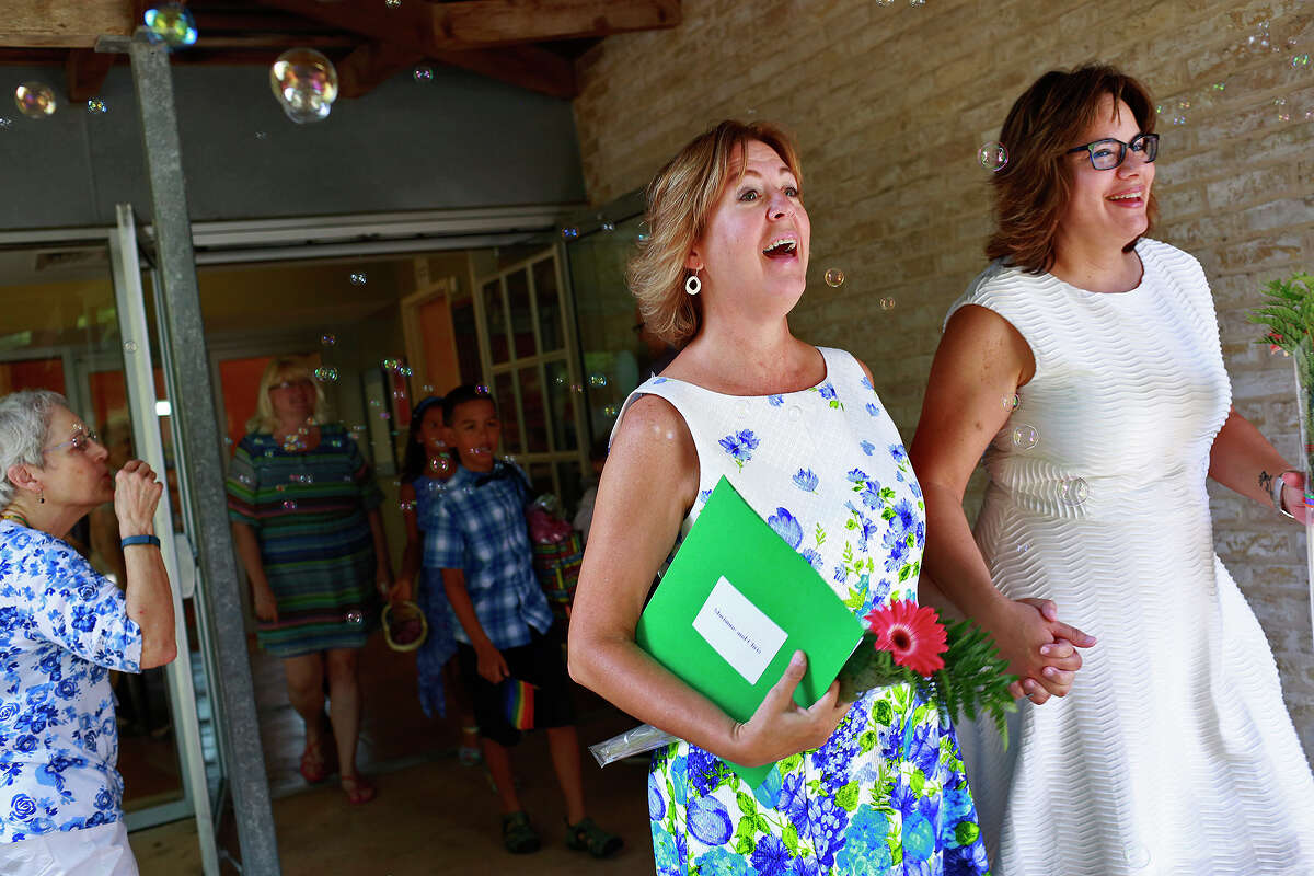 Church members blow bubbles as Marianne Laguna, left, and her wife, Chris Laguna, walk to their reception after their marriage ceremony at First Unitarian Universalist Church of San Antonio on Friday, July 3, 2015.