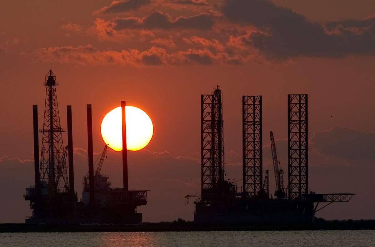 The sun sets behind two offshore oil platform rigs under construction in Port Fourchon, La.