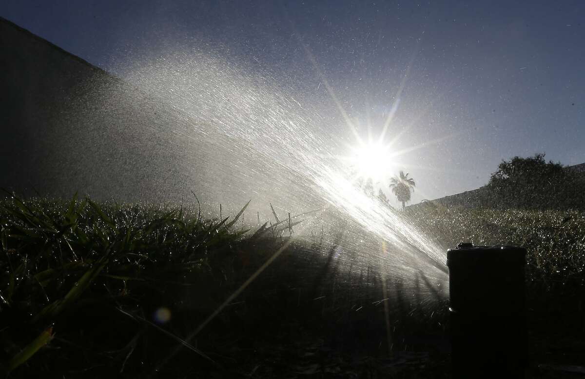 FILE - In this June 23, 2015, file photo a lawn is irrigated in Sacramento, Calif. The California Water Commission approved new rules that would essentially eliminate grass from new office and commercial buildings and reduce turf at new homes from a third of landscaped area to a quarter on Wednesday, July 15, 2015. (AP Photo/Rich Pedroncelli, File)