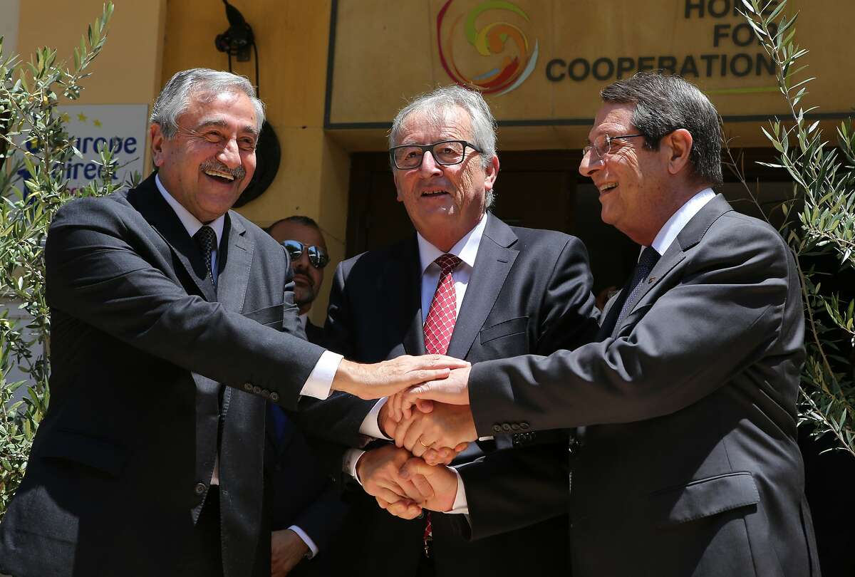 European Commission President Jean-Claude Juncker, centre, Cyprus' President Nicos Anastasiades, right, and Turkish Cypriot leader Mustafa Akinci, left, shake hands before their meeting inside the UN controlled buffer zone that divides the Cypriot capital, in Nicosia, Cyprus, July 16, 2015. Jean-Claude Juncker arrived in Cyprus for a two-day official visit. This is the first official visit of President Juncker to the island since he was elected as European Commission president. (AP Photos/Philippos Christou)